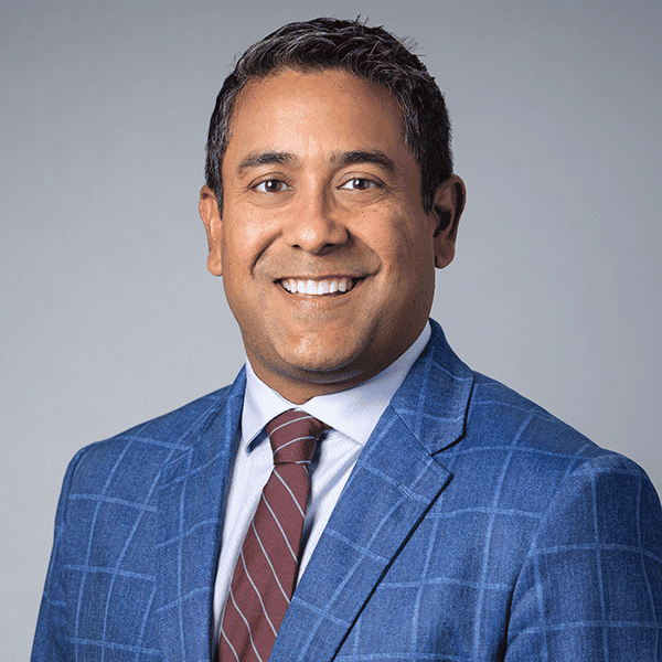 Man smiling in blue checkered suit and striped tie.