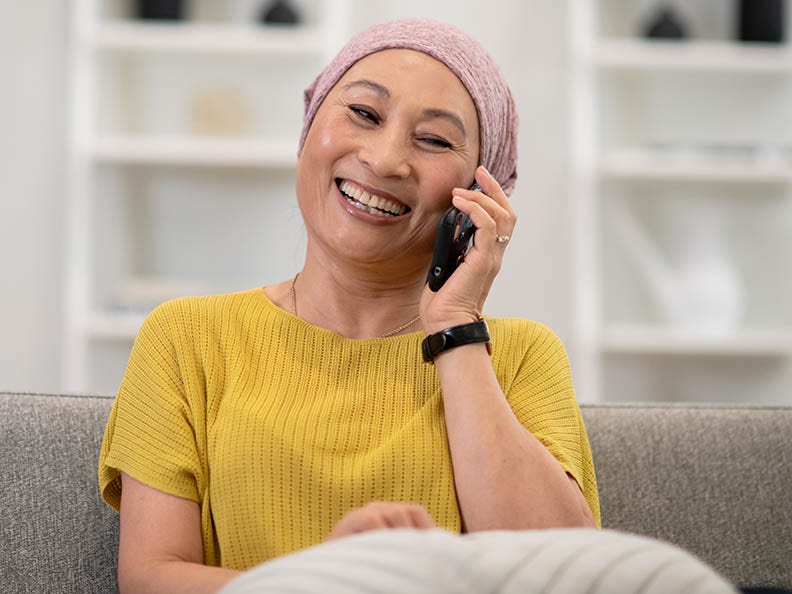 Woman wearing a headscarf and yellow shirt sitting and taking on the phone