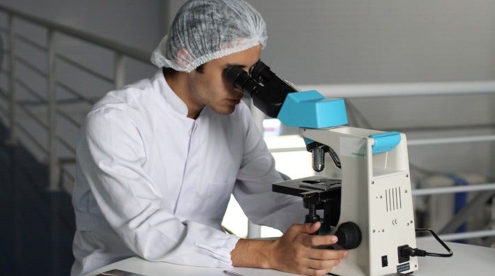 lab worker looking through microscope