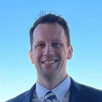 headshot of man with bright blue sky gray and gold tie 