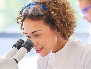 Woman scientist looking at a microscope. 