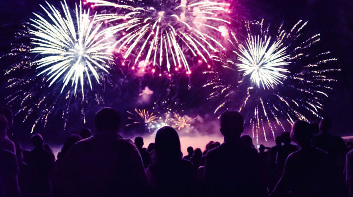 Silhouettes of people can be seen watching a fireworks display in the sky.