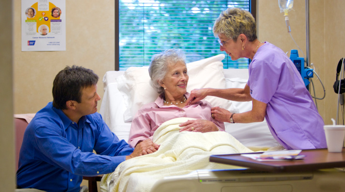 Nurse speaking to patient and caregiver in hospital room