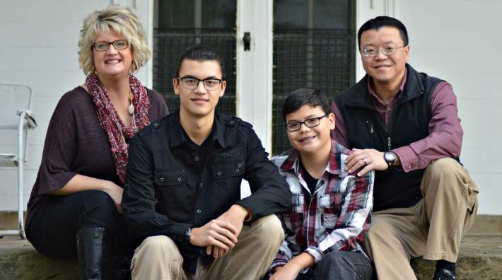 Jill Chang, her husband and two sons sitting on porch steps