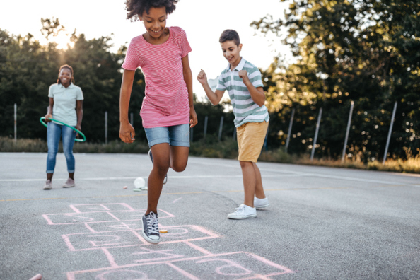 Multiracial group of kids playing hopscotch outside