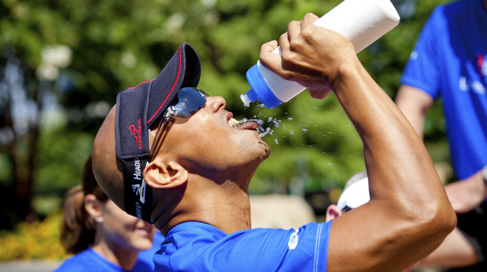 man drinks water from a bottle after completing a race