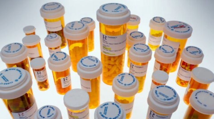 A range of prescription medication bottles stand against a white background.
