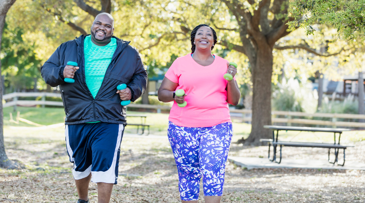 couple walking in park and holding hand weights