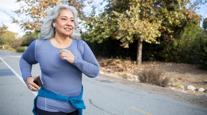 senior woman jogging outside with earphones