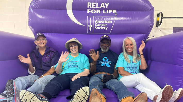 Bobbie Parker with fellow volunteers sitting in large purple inflatable chair at a Relay for Life event