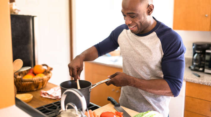 smiling man cooking using assorted vegetables