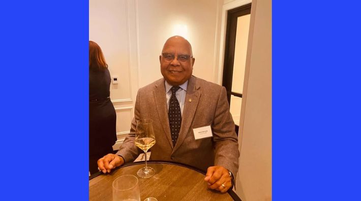 Jesse Bennett smiles at a dinner table while wearing a tailored suit