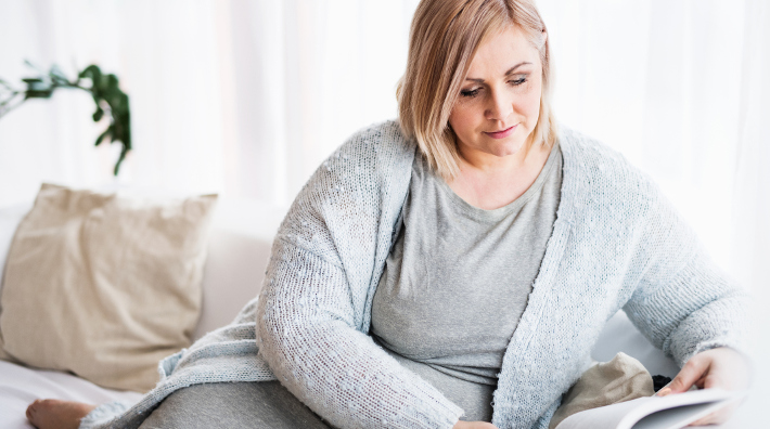 attractive overweight woman sitting on couch reading a book