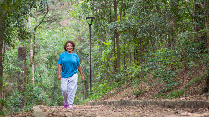 happy woman walks outside in wooded area