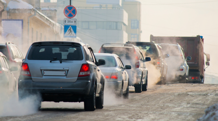traffic jam on city streets with exhaust fumes coming from cars