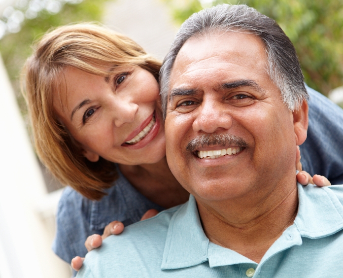Senior couple relaxing in garden smiling to camera