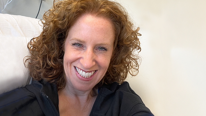 Smiling woman with curly red hair relaxing indoors.