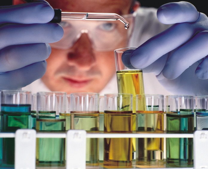 male researcher dropping liquid into test tubes