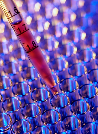 a dropper drops colored liquid into test tubes in lab
