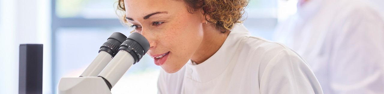 Female research scientist looking into a microscope in the lab