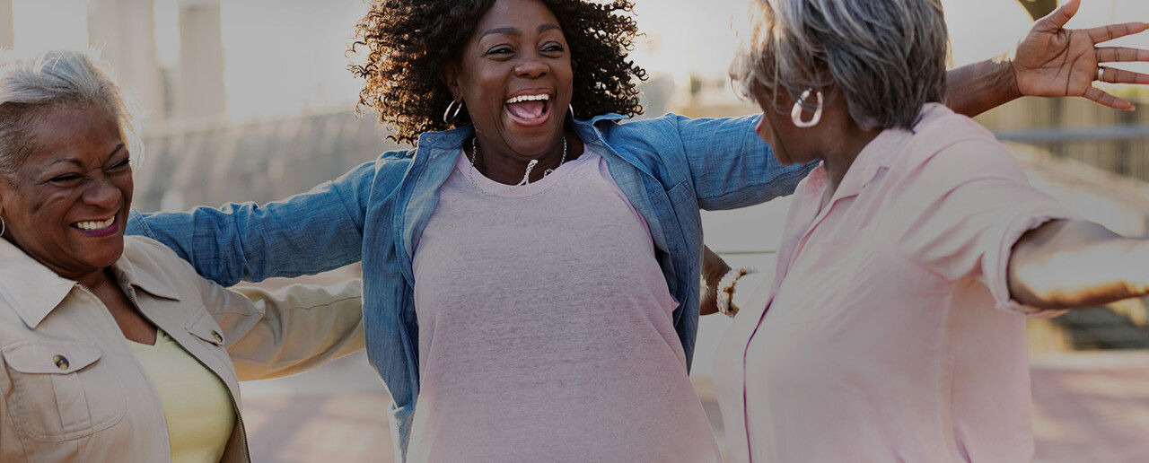 Three black women excitedly embracing 