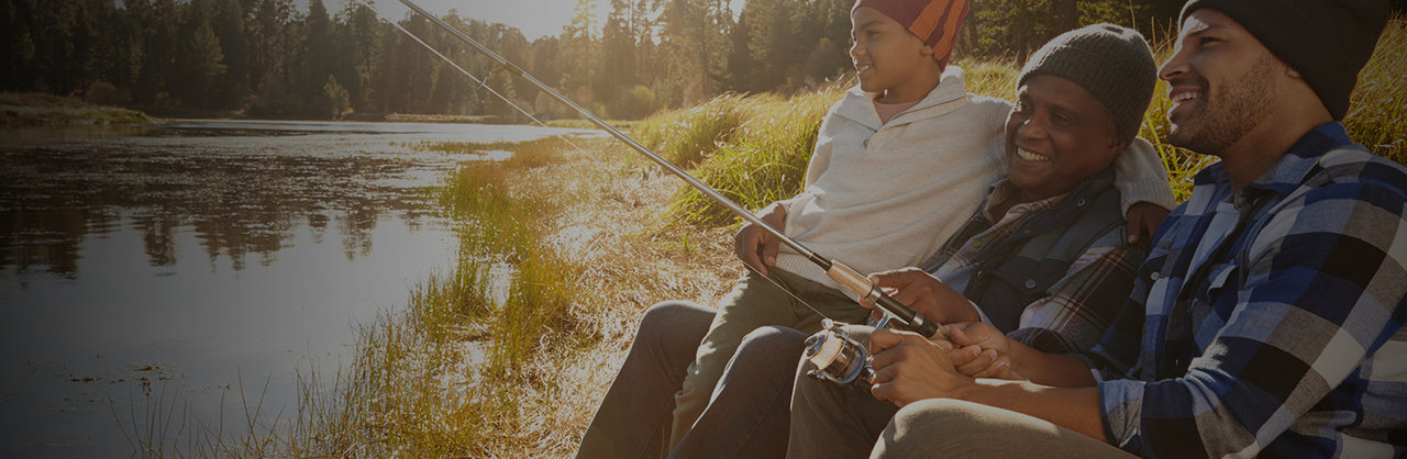 black father son and grandfather sitting by the lake fishing