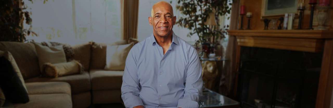 black man in crisp blue dress shirt sitting in living room