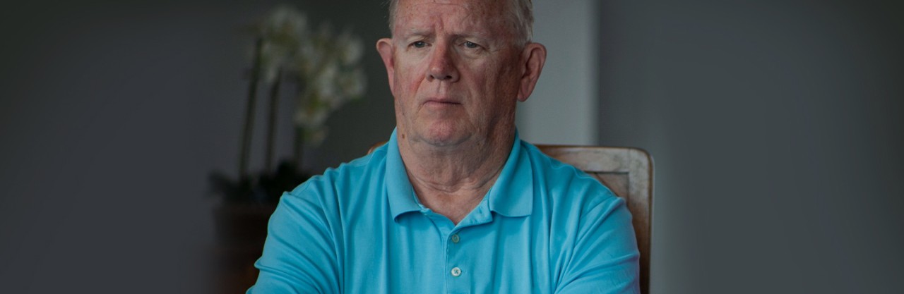 caucasian male in blue shirt sitting in chair facing the camera