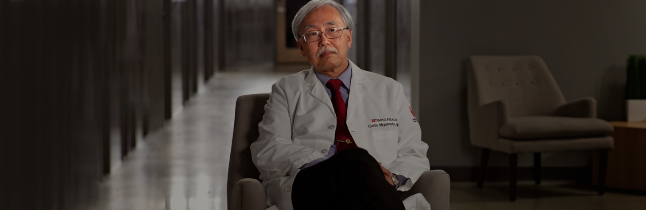 Asian doctor wearing white coat sitting in chair 