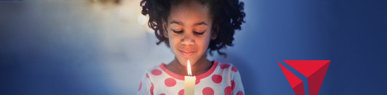 Banner image of a little girl holding a candle with the Delta logo visible
