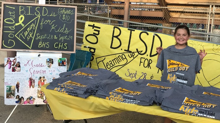 Maddie Stanton helping to sell Gold Out shirts at a local football game for childhood cancer research