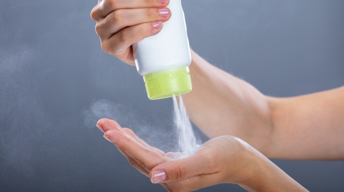 close up of woman's hands as she squeezes talcum powder from bottle