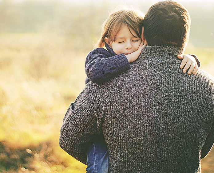 A father carrying his child in a sunny field
