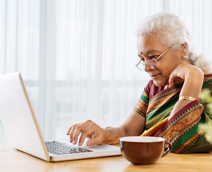 Serious elderly Indian woman working on laptop