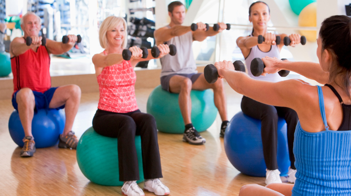 diverse group work out with weights and exercise balls during a class in studio