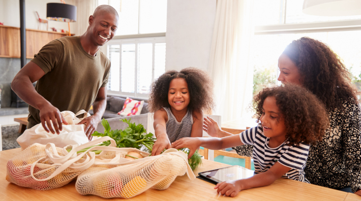 family unpacking plastic grocery bags in kitchen