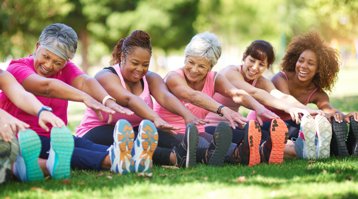 diverse group of women stretching outside before exercise