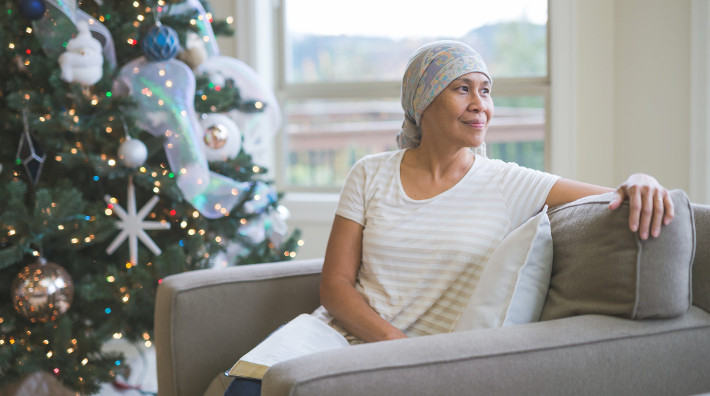 woman in head scarf sitting beside Christmas tree