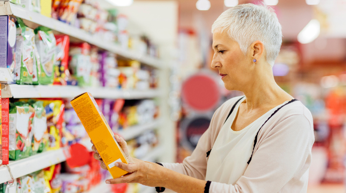 woman reads package label of item in grocery store
