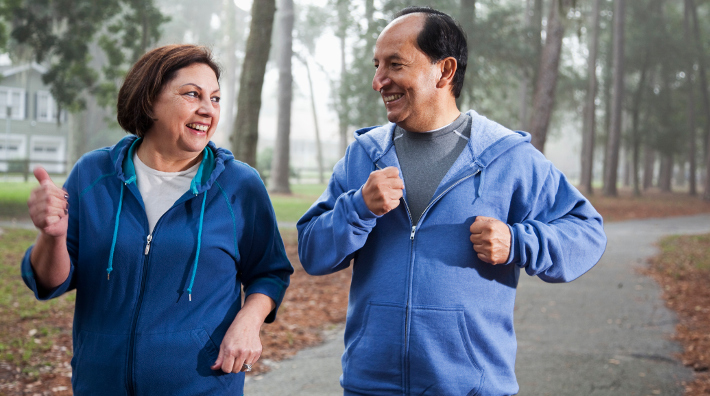 middle aged Hispanic couple walk for exercise in park