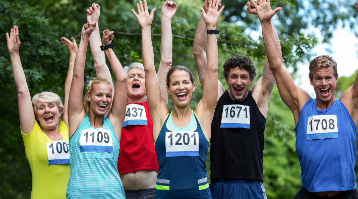a group of male and female runners celebrate after completing a race
