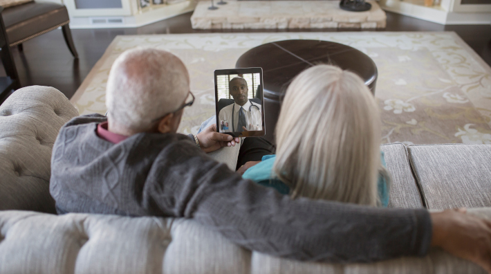 older couple talking with doctor via tablet at home