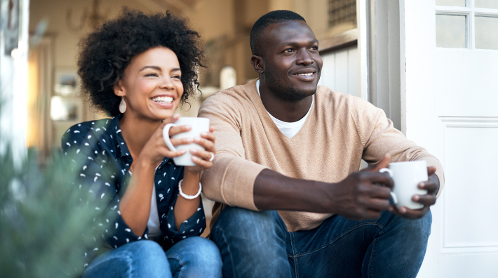 happy young couple drink coffee outside their home