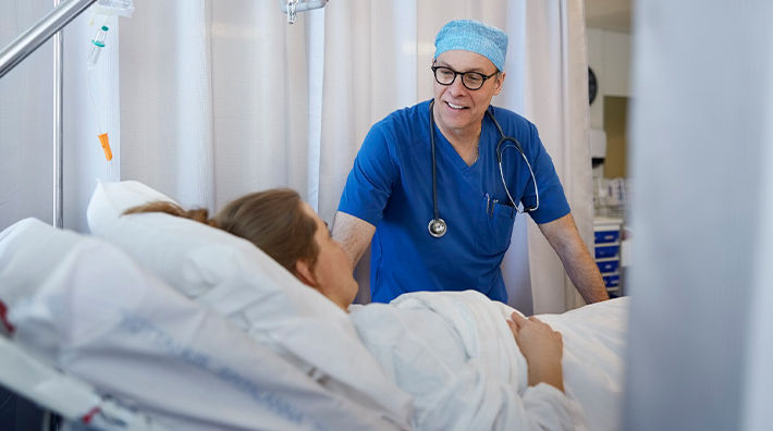 Doctor Talks to Woman in Hospital Bed