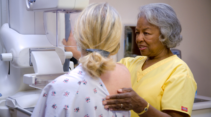 nurse prepares woman for a mammogram