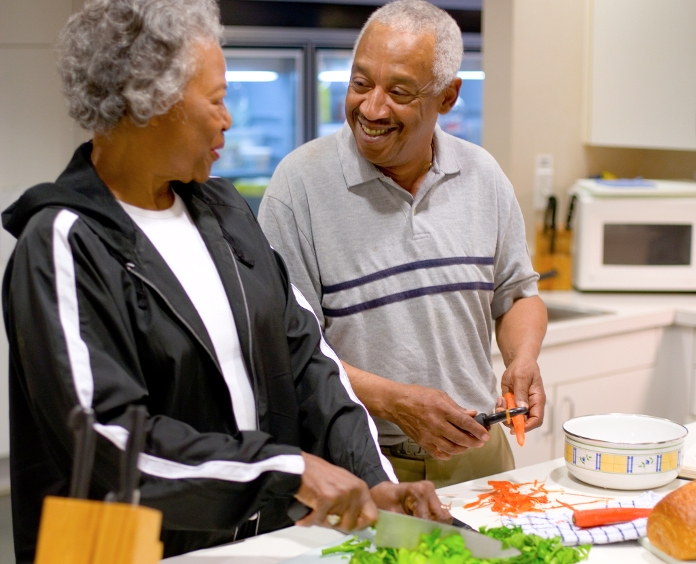 senior couple chopping lettuce and carrots in kitchen