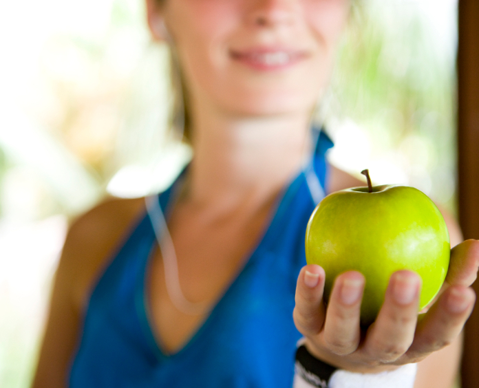 close up of woman's hand as she holds a green apple