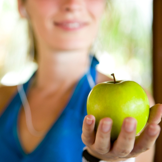 close up of woman's hand as she holds a green apple