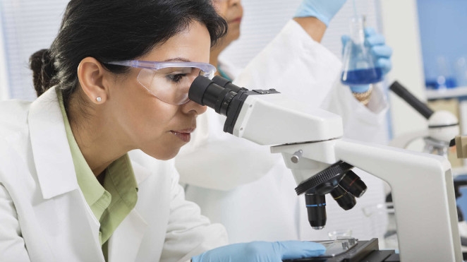 female researcher using microscope in lab