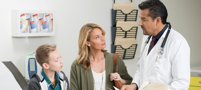 a male teen and his mother listen to their doctor in exam room